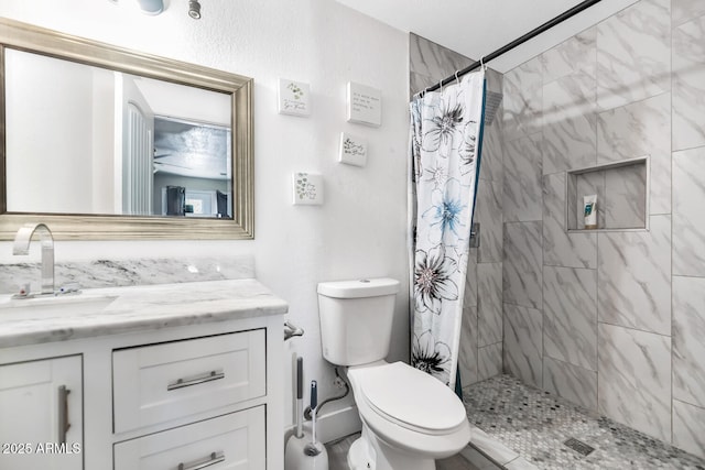 bathroom featuring vanity, a tile shower, and toilet
