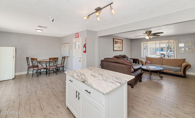 kitchen with visible vents, freestanding refrigerator, a textured ceiling, and light wood-style floors