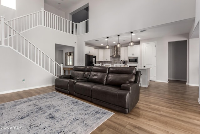 living room with a towering ceiling and light wood-type flooring