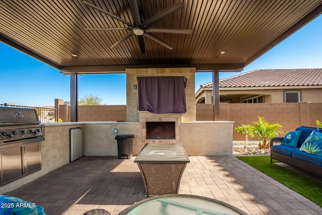 view of patio / terrace with ceiling fan, an outdoor living space with a fireplace, and area for grilling