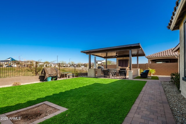 view of yard featuring ceiling fan, a fireplace, area for grilling, and a patio