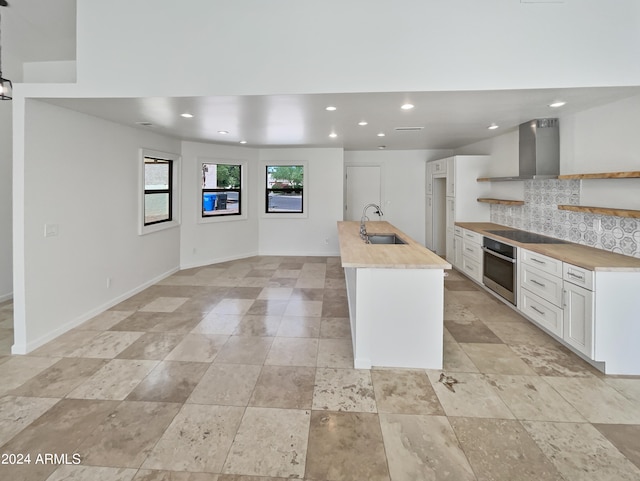 kitchen featuring sink, wall chimney range hood, black electric cooktop, stainless steel oven, and tasteful backsplash