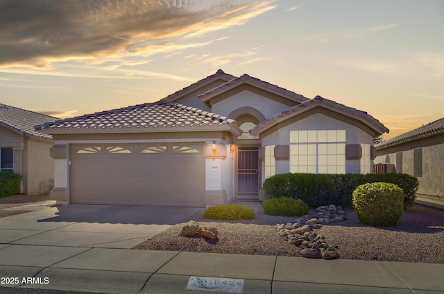 view of front of property with a tiled roof, a garage, driveway, and stucco siding