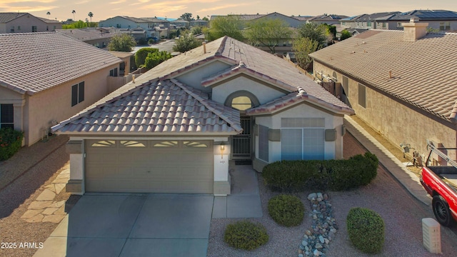 view of front of home featuring stucco siding, driveway, a tile roof, a residential view, and an attached garage