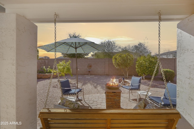 patio terrace at dusk featuring a fire pit and a fenced backyard