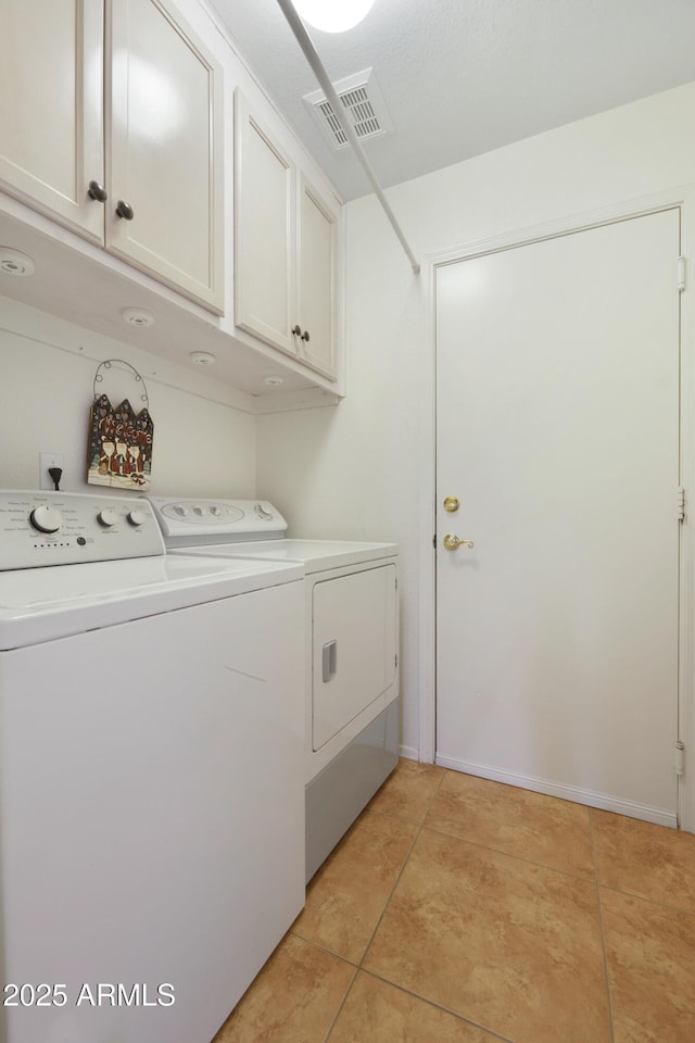 washroom with light tile patterned floors, cabinet space, visible vents, and washing machine and clothes dryer