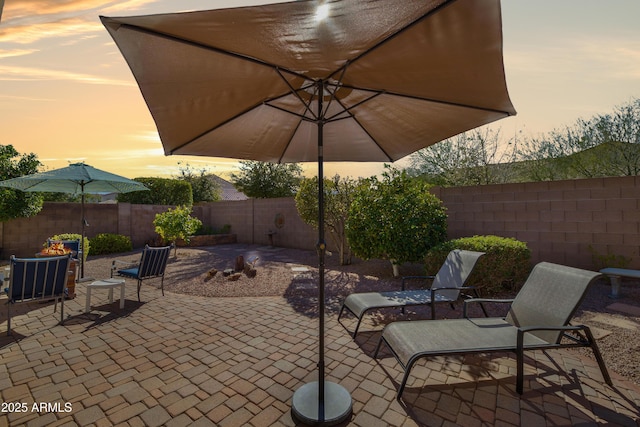 patio terrace at dusk featuring a fenced backyard