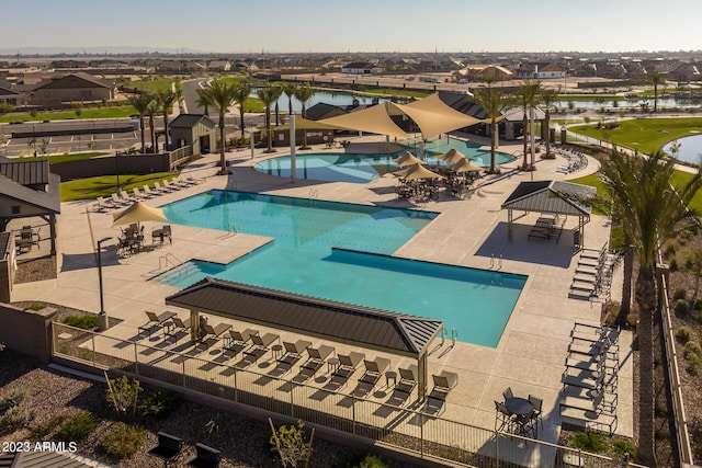 pool featuring a patio, fence, a residential view, and a water view