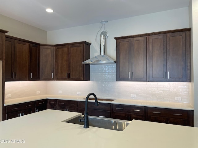 kitchen featuring dark brown cabinetry, light countertops, stovetop, and a sink