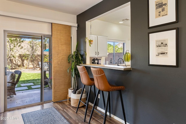 bar with visible vents, a sink, baseboards, and wood finished floors