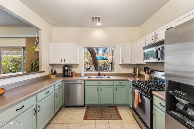 kitchen featuring visible vents, green cabinets, appliances with stainless steel finishes, white cabinetry, and a sink