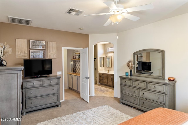 bedroom featuring arched walkways, ensuite bathroom, visible vents, and light colored carpet