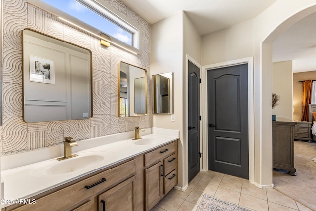 full bath featuring ensuite bathroom, double vanity, tile patterned flooring, and a sink