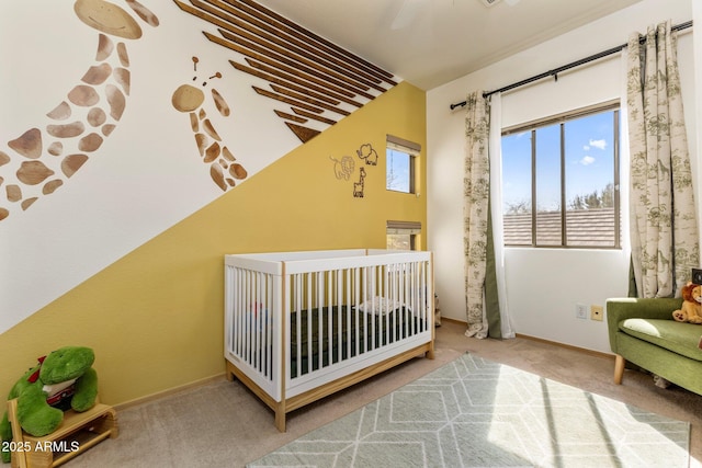 bedroom with a nursery area, carpet, and baseboards