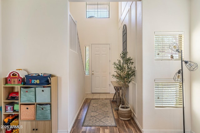 entrance foyer featuring a towering ceiling, baseboards, and wood finished floors