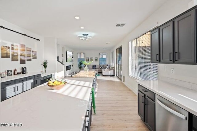 kitchen featuring visible vents, stainless steel dishwasher, open floor plan, light wood-style floors, and light countertops