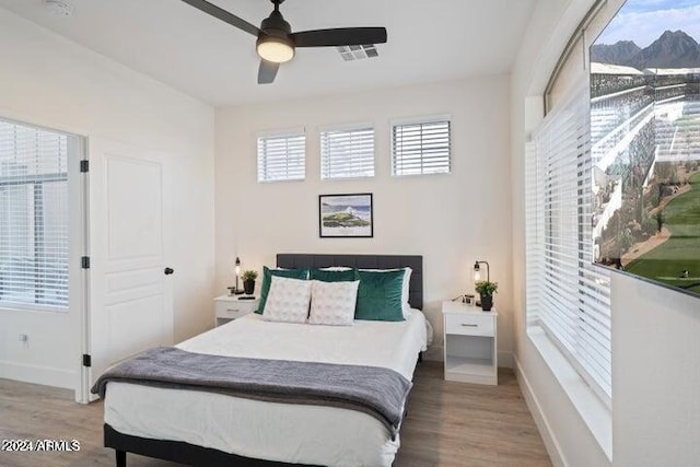 bedroom featuring ceiling fan, visible vents, baseboards, and wood finished floors