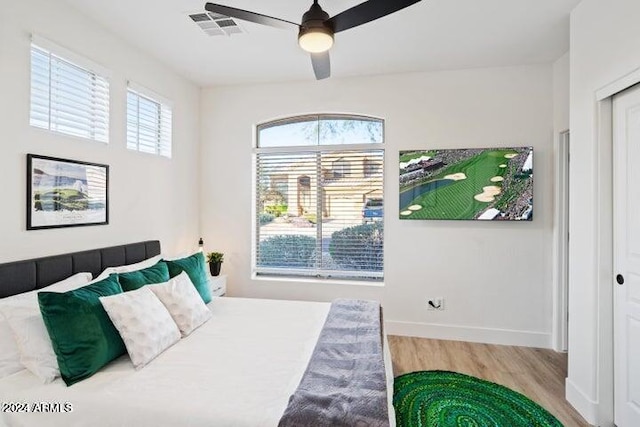 bedroom featuring visible vents, multiple windows, baseboards, and wood finished floors