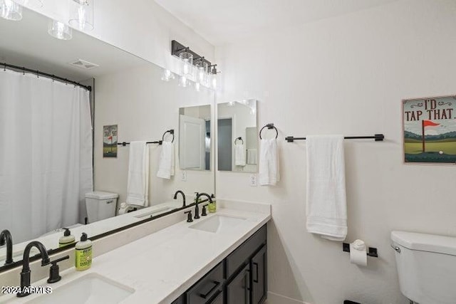 full bath with a sink, toilet, and double vanity