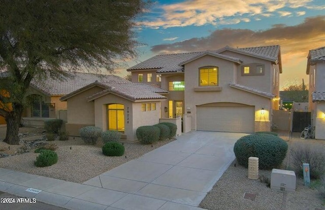 view of front facade featuring a tiled roof, concrete driveway, stucco siding, a garage, and a gate