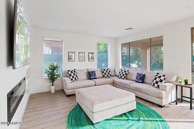 living area with a wealth of natural light, visible vents, and light wood-type flooring