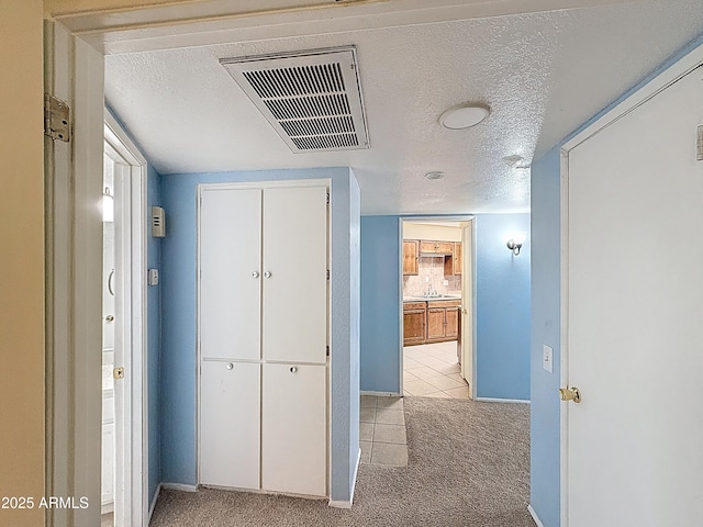 1553 E Flower Cir, Mesa, AZ 85204 - hall with light colored carpet, baseboards, a textured ceiling, a sink, and light tile patterned floors