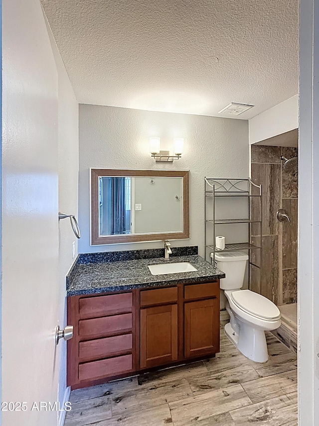 1553 E Flower Cir, Mesa, AZ 85204 - full bathroom with a textured ceiling, a tile shower, toilet, vanity, and wood finished floors