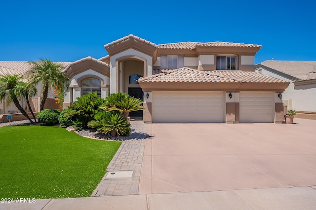 mediterranean / spanish house featuring a garage and a front lawn