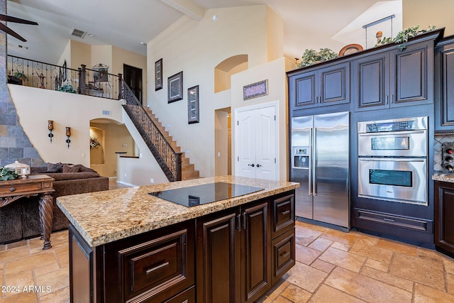 kitchen featuring beam ceiling, a kitchen island, stainless steel appliances, and high vaulted ceiling