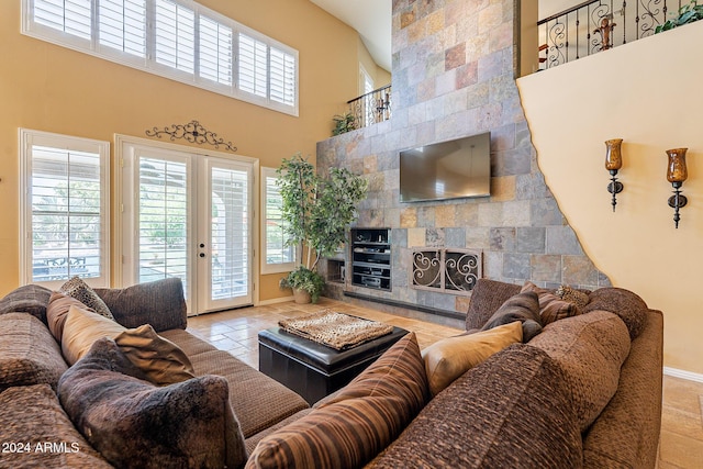 living room with a tile fireplace, french doors, and a high ceiling