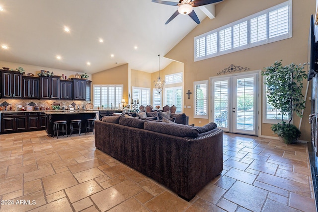 living room with ceiling fan with notable chandelier, a towering ceiling, and french doors