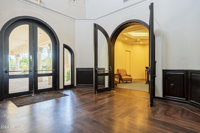 foyer featuring a towering ceiling, french doors, dark parquet floors, and a notable chandelier