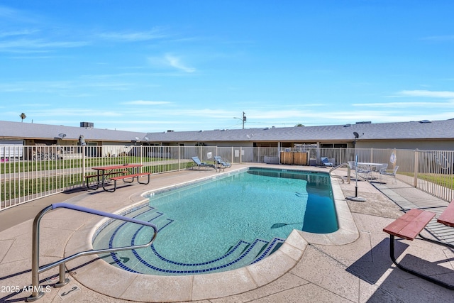 community pool with a patio area and fence