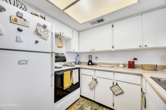 kitchen featuring white appliances, light countertops, visible vents, and white cabinetry