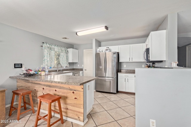 kitchen featuring a kitchen bar, kitchen peninsula, white cabinets, and appliances with stainless steel finishes