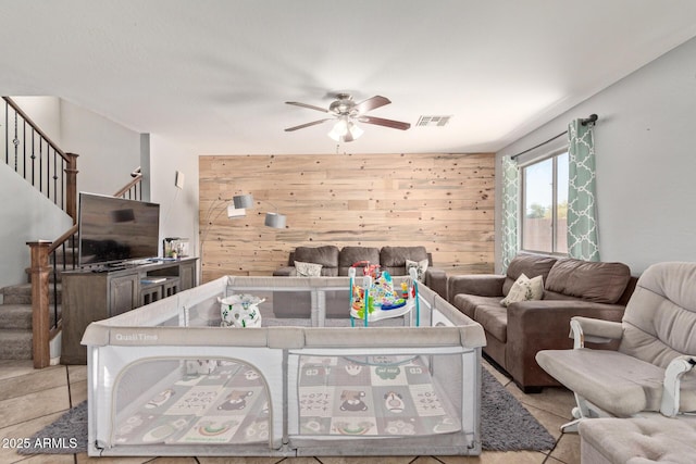 tiled living room featuring wooden walls and ceiling fan