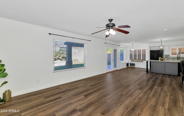 unfurnished living room with ceiling fan, sink, dark wood-type flooring, and french doors