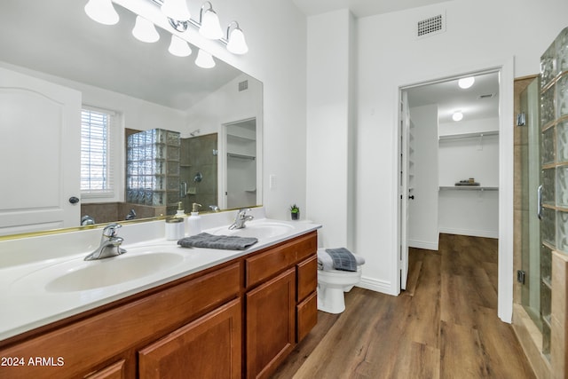 bathroom featuring hardwood / wood-style floors, vaulted ceiling, toilet, vanity, and a shower with shower door