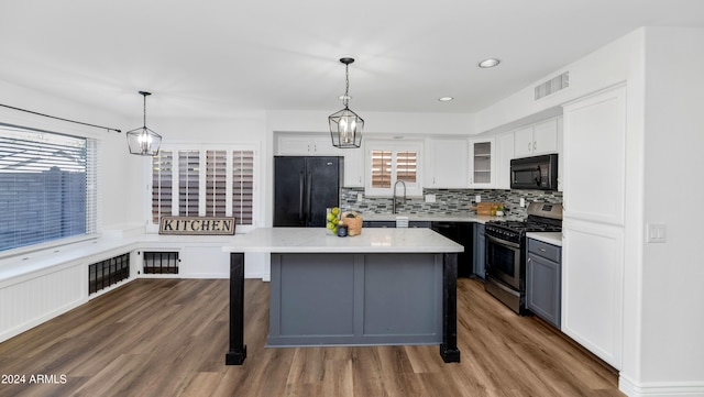 kitchen with black appliances, white cabinets, hanging light fixtures, dark hardwood / wood-style floors, and plenty of natural light