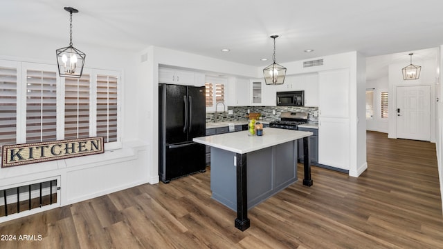 kitchen featuring dark hardwood / wood-style flooring, pendant lighting, a kitchen island, and black appliances