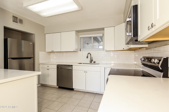 kitchen with white cabinetry, tasteful backsplash, light tile patterned floors, stainless steel appliances, and sink