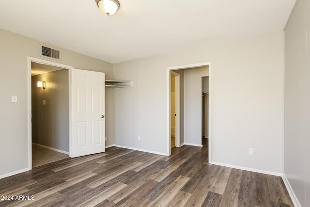 unfurnished bedroom with a closet and dark hardwood / wood-style flooring