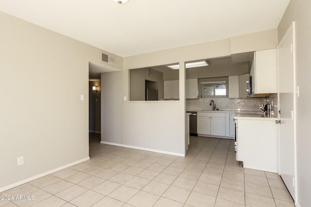 kitchen with appliances with stainless steel finishes, white cabinetry, backsplash, light tile patterned floors, and sink