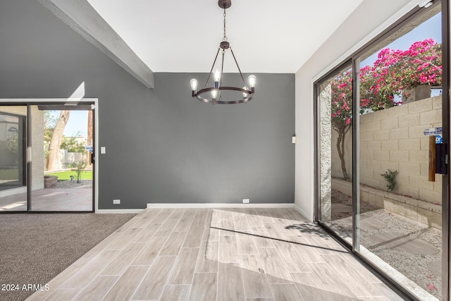 interior space featuring a high ceiling, plenty of natural light, a notable chandelier, and light carpet