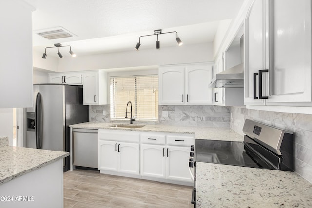 kitchen featuring stainless steel appliances, white cabinetry, wall chimney exhaust hood, sink, and light stone counters