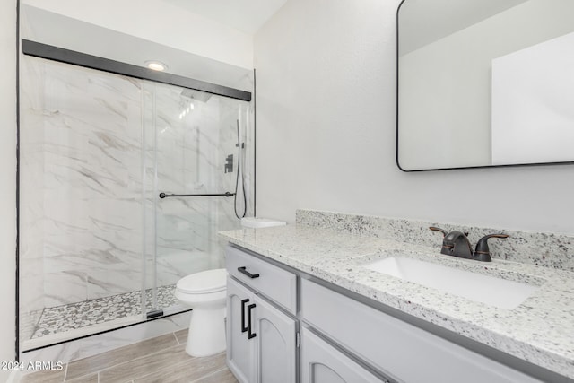 bathroom featuring tile patterned flooring, toilet, a shower with door, and vanity