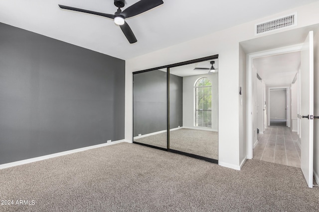 unfurnished bedroom featuring ceiling fan, a closet, and light carpet