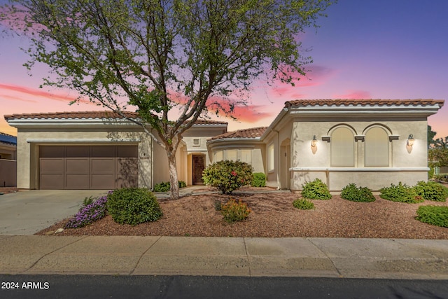 mediterranean / spanish-style house featuring a tiled roof, a garage, driveway, and stucco siding