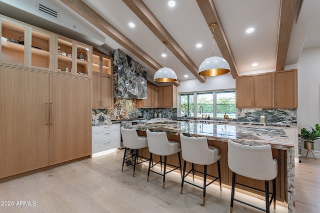 kitchen featuring tasteful backsplash, light stone counters, and light wood-type flooring