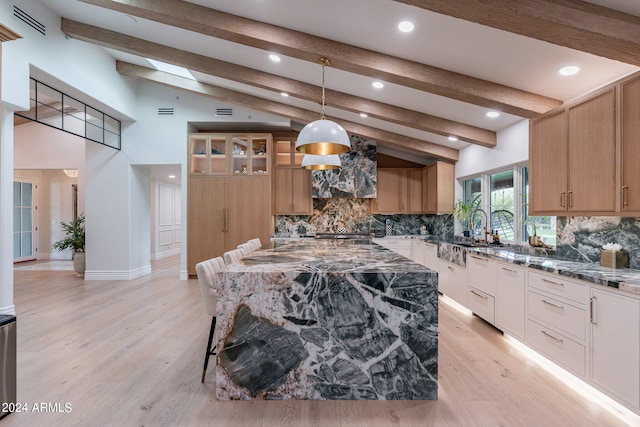 kitchen featuring dark stone countertops, lofted ceiling with skylight, light hardwood / wood-style floors, and a kitchen island